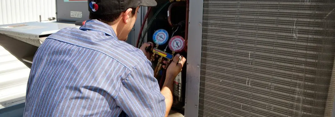 HVAC technician servicing a condenser unit in Stonecrest